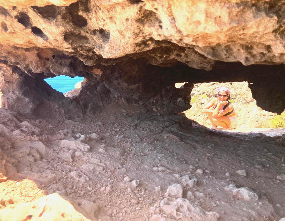 Explorando lo que hay detrás del síntoma Flor agachada junto a una cueva de roca, simbolizando la exploración interior y el descubrimiento de lo oculto en el proceso de sanación – Espacio Medrar